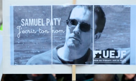 A placard with the portrait of history teacher Samuel Paty as people gather in Paris.