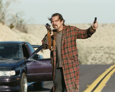 Leonardo DiCaprio standing beside a car holding a gun