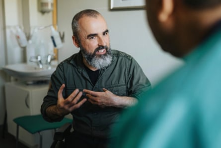 Male patient gestures while talking to a doctor in clinic.