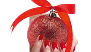 Shiny red bauble with red bow on top, held by red-nailed hand