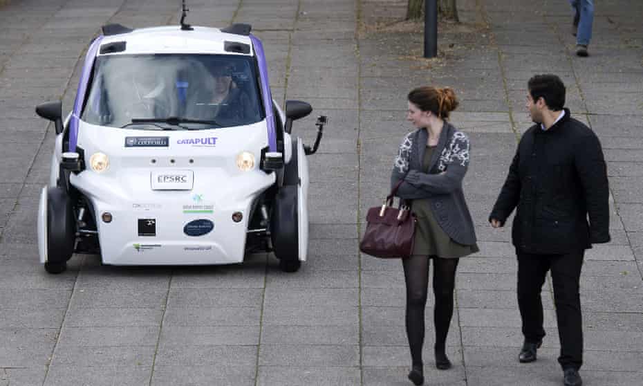 People look towards an autonomous self-driving vehicle, as it is tested in  in Milton Keynes