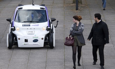 People look towards an autonomous self-driving vehicle, as it is tested in a pedestrianised zone, during a media event in Milton Keynes