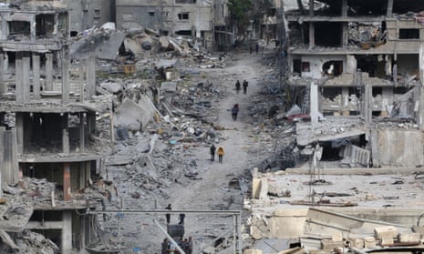 Palestinians walk past damaged buildings in Khan Yunis on April 8, 2024.