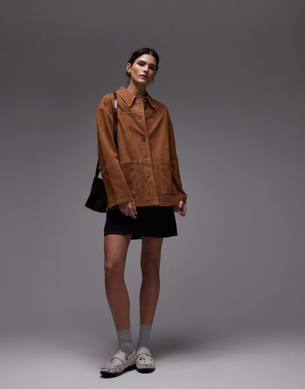 Model wearing tan suede jacket black short skirt and trainers