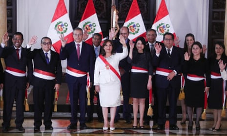 Peru's President Boluarte presents her new cabinet wearing red and white sashes against a backdrop of Peruvian flags