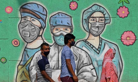 Commuters in Delhi pass a mural depicting masked medics
