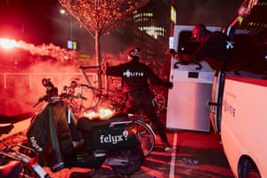 A riot police officer throws a flare into a canal.