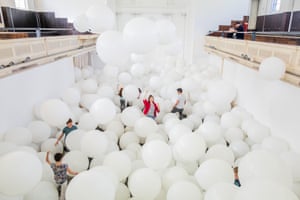 People stand and walk among large white balloons