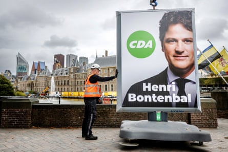 An employee installs an election sign on a bridge over a canal showing Henri Bontenbal