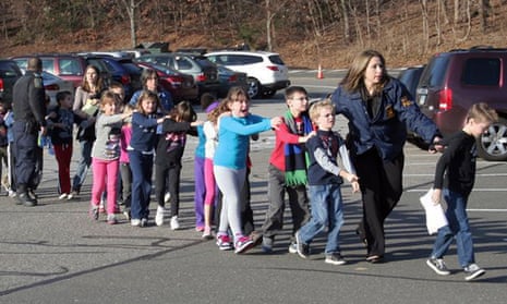 In this photo provided by the Newtown Bee, Connecticut state police lead children from the Sandy Hook elementary school following a shooting there in 2012.