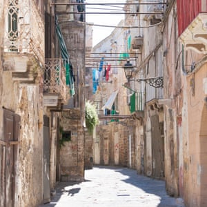 Narrow street with washing lines between buildings, Taranto, Italy.