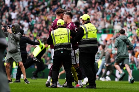 Lawrence Shankland is escorted from the Celtic Park pitch by security