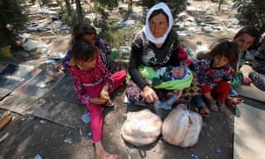 A Yazidi woman and her children fleeing violence in Sinjar rest at the Iraq-Syria border, 2014