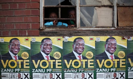 Children look through a window above election posters of Emmerson Mnangagwa