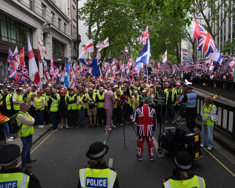 Police and crowd marshals form a line in front of protesters holding union jack and Saint George's cross flags