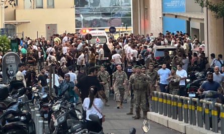 Lebanese soldiers, Hezbollah members and members of the public gather outside a hospital entrance