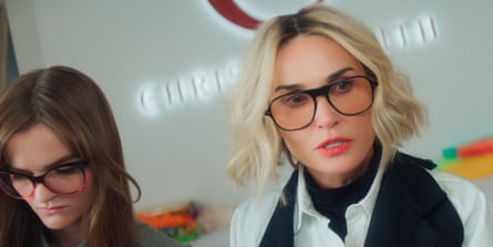 A blond lady wearing tinted glasses and a white shirt