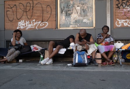 People lean against the wall of a building while sitting on the pavement
