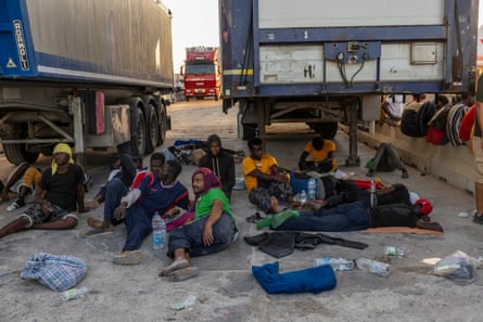 People lie on the ground in Lampedusa waiting to board a ship that will transfer them to Sicily.