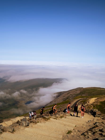 Walkers ascend Yr Wyddfa via the Llanberis path on a fine day.