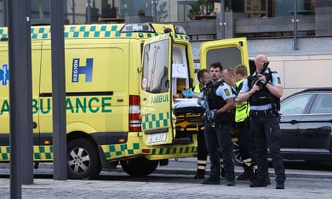 Armed police look out next to patient being lifted into ambulance outside the Field's shopping center in Orestad. Copenhagen shopping centre shooting: with a suspect in custody, police in Denmark have appealed for anyone who has seen, heard or filmed anything to contact them about the mall attack that left several people dead.