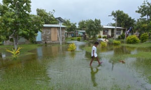 Fijian girl walks over flooded land in her village.