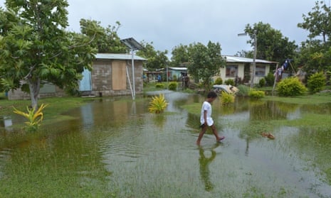 Fijian girl walks over flooded land in her village.