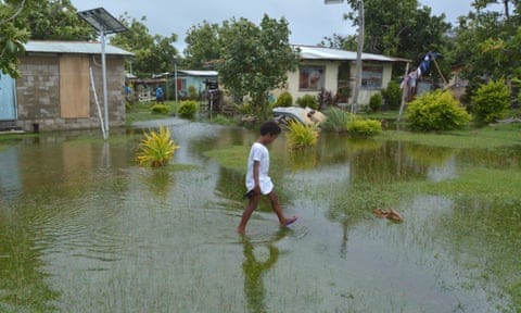 A girl walks over flooded land in Fiji