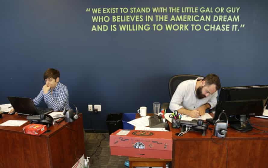 April Gracz, left, and Pano Giannakopoulos, right, Gravity Payments workers next to a wall displaying a company mission statement.