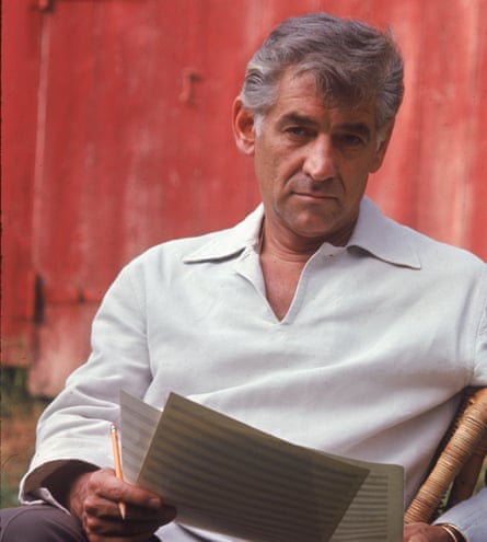 a man with grey hair and a white shirt holding a pencil and sheet music