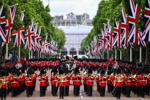 Members of the King’s Guard march and play music below rows of union flags outside Buckingham Palace