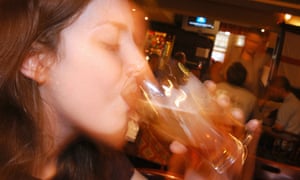 A young woman drinking a pint of beer