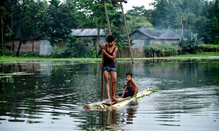 Indian children paddle a raft through floodwaters at Kalgachia in Barpeta district in India’s northeastern state of Assam