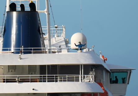 A man in a face mask and hat onboard the ship.