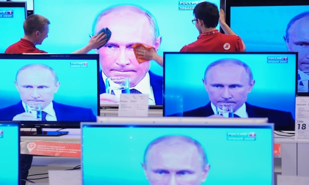 Vladimir Putin is seen on multiple television screens.