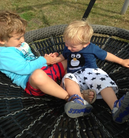 Two toddlers playing together on a trampoline.