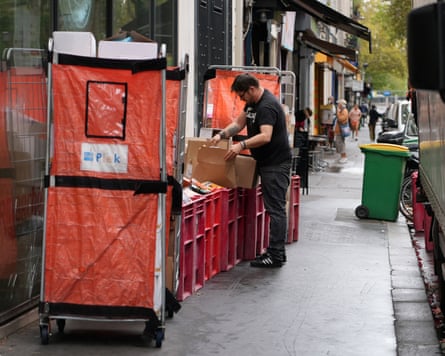 An employee sorts boxes of perished goods beside red crates outside a Paris supermarket