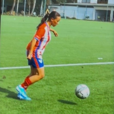 A grainy pic of a woman on a pitch about to kick a football