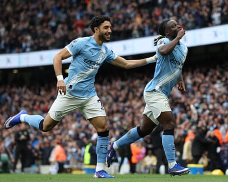 Manchester City players Jeremy Doku and Omar Marmoush celebrate on the pitch during a match.