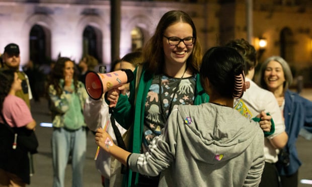 Participants in Nightwalks with Teenagers, a global social art experiment that sees teenagers lead adults on a tour of their city.  One teen holding a megaphone can be seen laughing and smiling at another teen, who is facing away from the camera