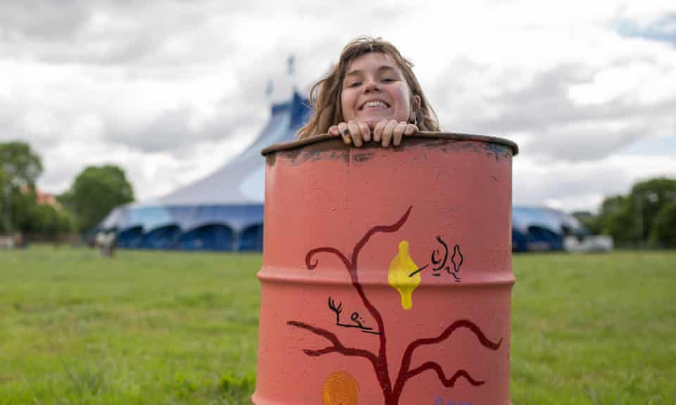 Bethany Stenning, a bin painter who will perform with Ishmael Ensemble at West Holts stage on Sunday morning, peeks out from inside a bin.