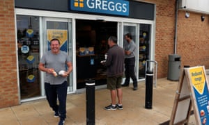 People are seen outside a Greggs store.