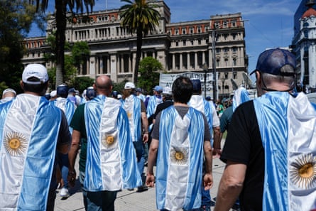Protesters draped with Argentinian national flags walk towards the supreme court building