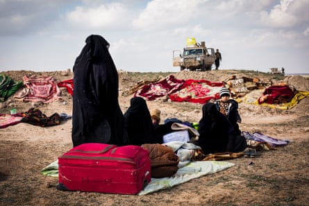 Women and children seen sitting on blankets with their few belongings at a civilian screening point
