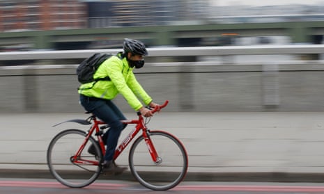 A cyclist wearing a mask cycles across London Bridge. 