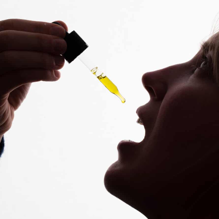 A woman taking drops of CBD oil
