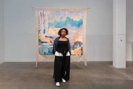 Cutting-edge labs, a rainforest gallery and guesthouse: Nigeria to open art museum for 21st century A woman stands in front of a painting that is suspended from the ceiling.