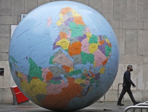 London, England: a pedestrian passes a globe designed by Mark Wallinger called ‘The World turned Upside Down’