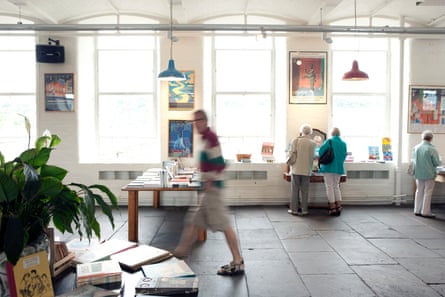 People browse tables of books in an airy space with art on the walls