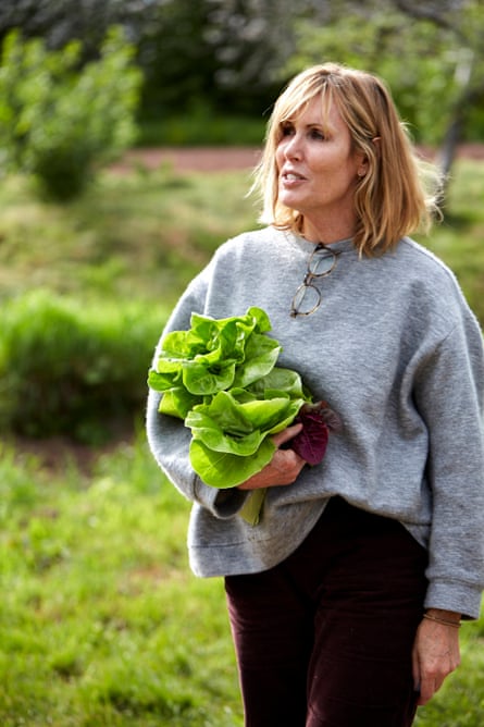 Chef Skye Gyngell stands in a garden holding lettuce